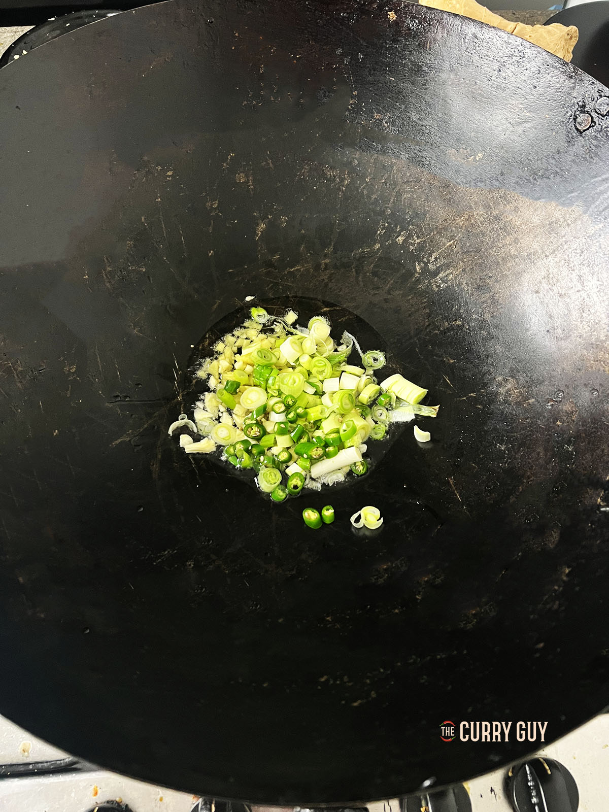 Frying the garlic, ginger, spring onions (scallions) and chillies.