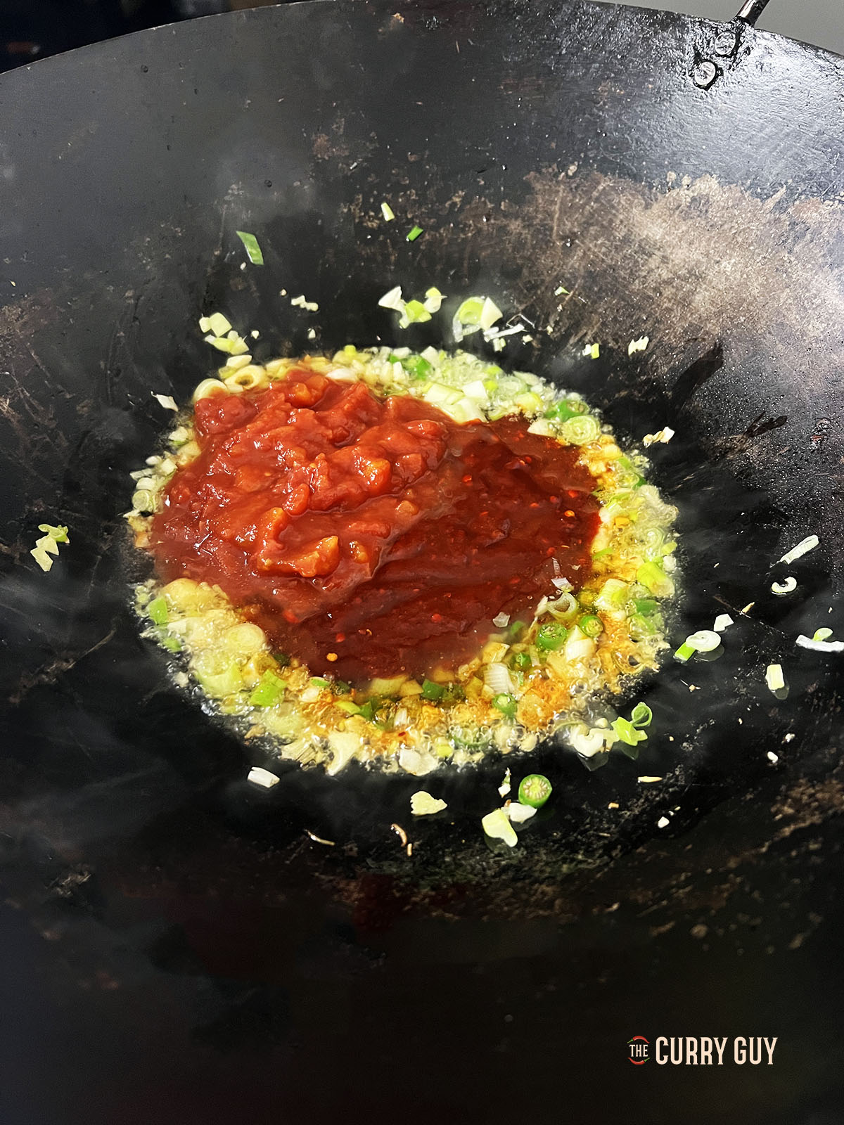Adding the gochujang sauce and chopped tomatoes.
