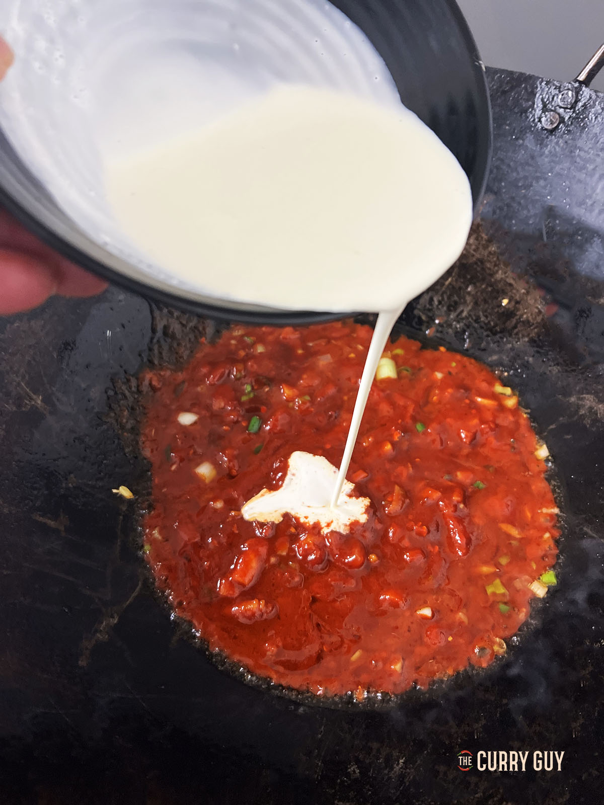 Adding the cream to the sauce.