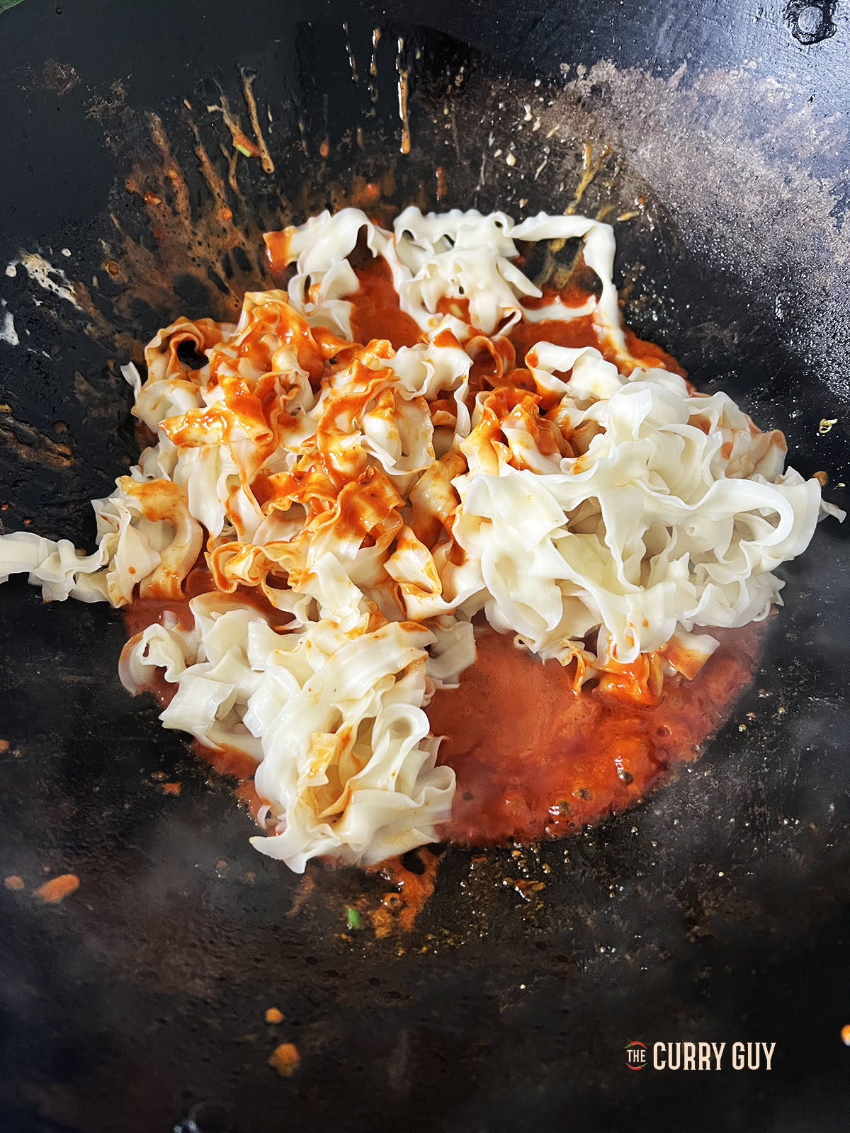 Adding the pasta to the gochujang sauce.