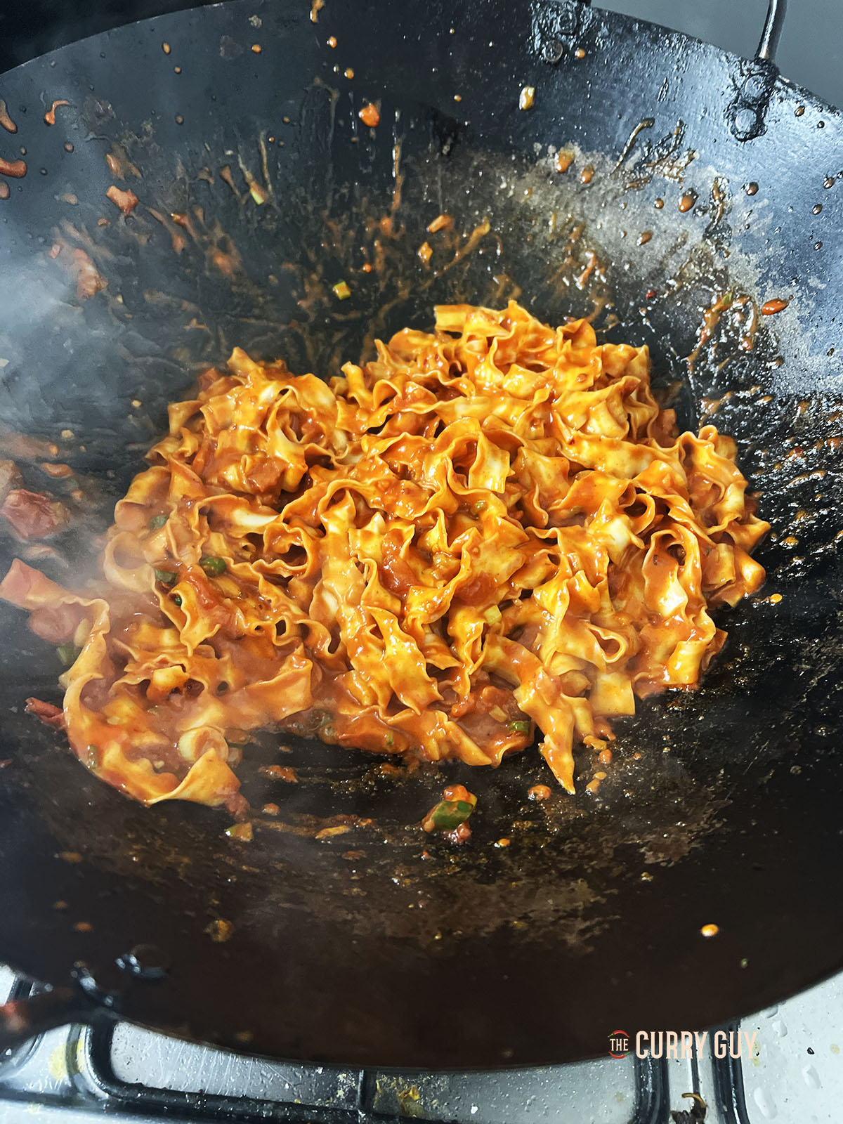 Stirring the pasta into the sauce to coat.