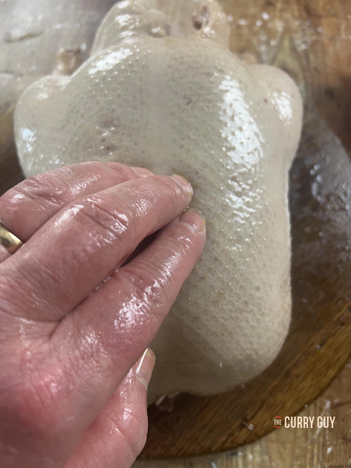 Seasoning the duck with salt and rubbing the maltose solution into the skin.