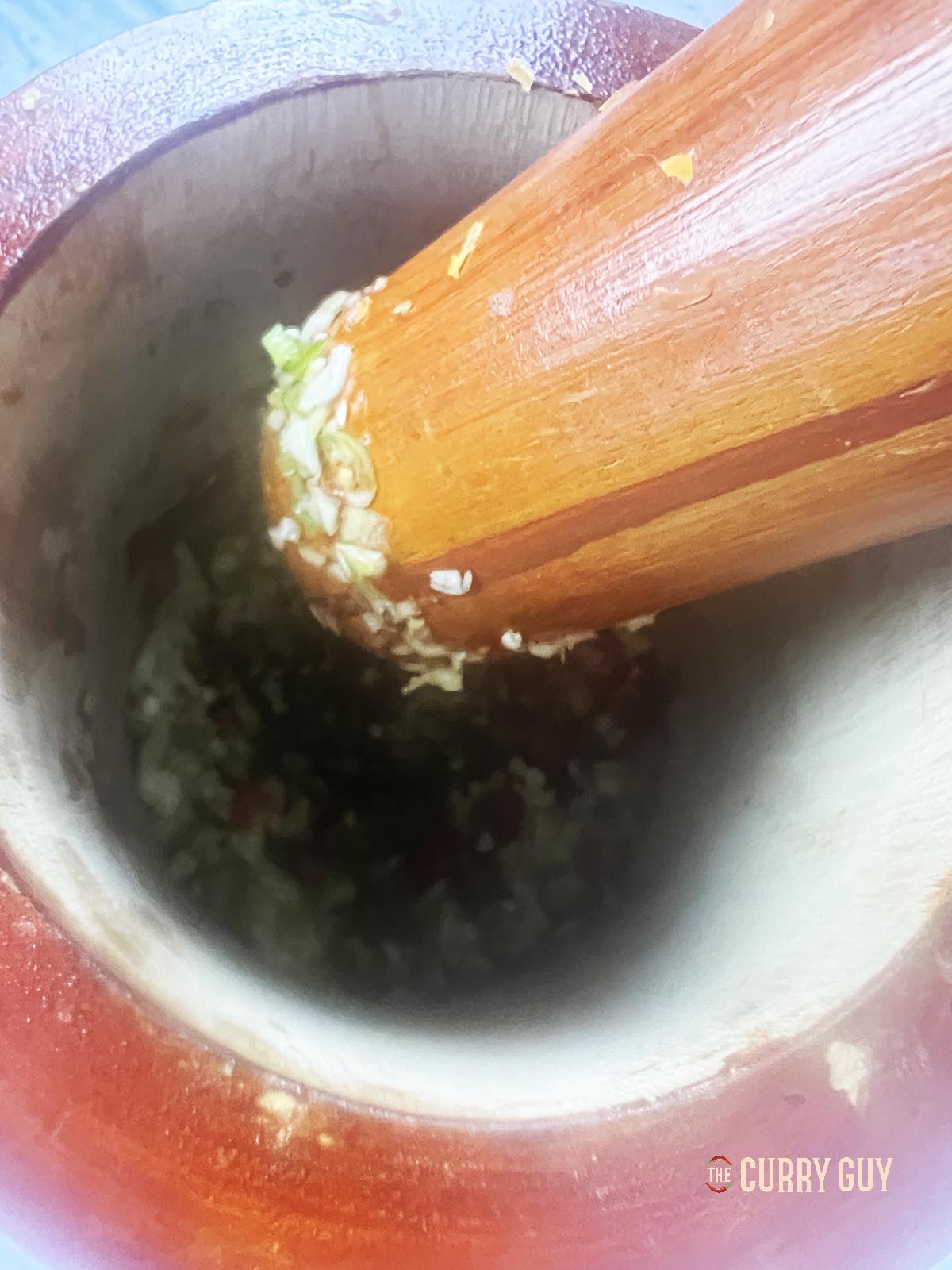 Pounding the chillies, garlic and coriander (cilantro) stems in a pestle and mortar.