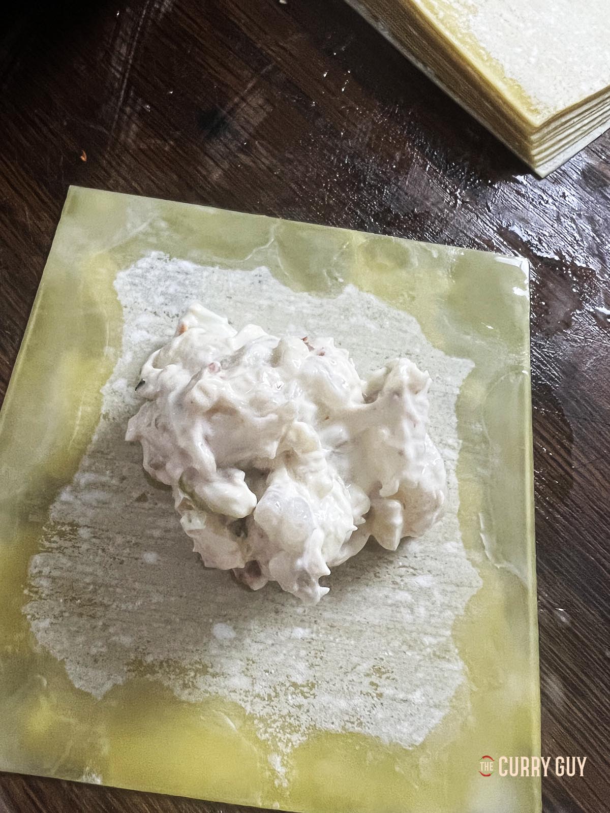 Placing a tablespoon of the filling in the centre of the wonton wrapper.