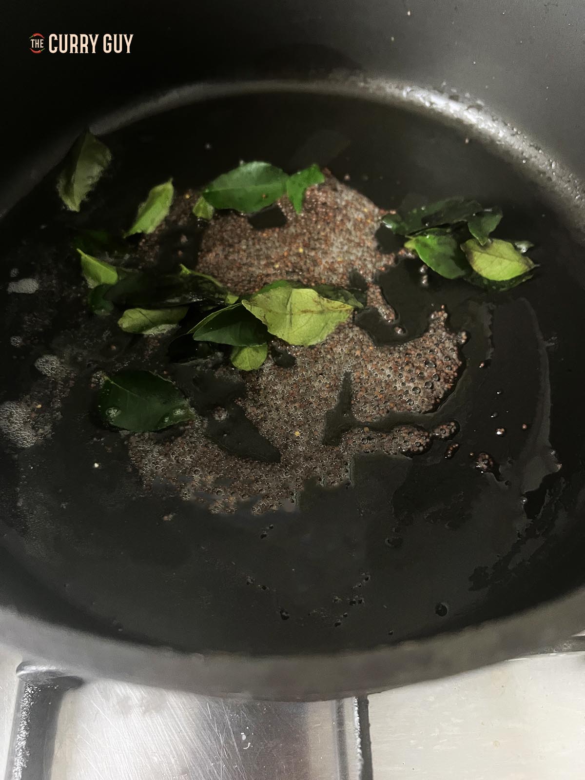 Tempering the mustard seeds and curry leaves in the coconut oil.
