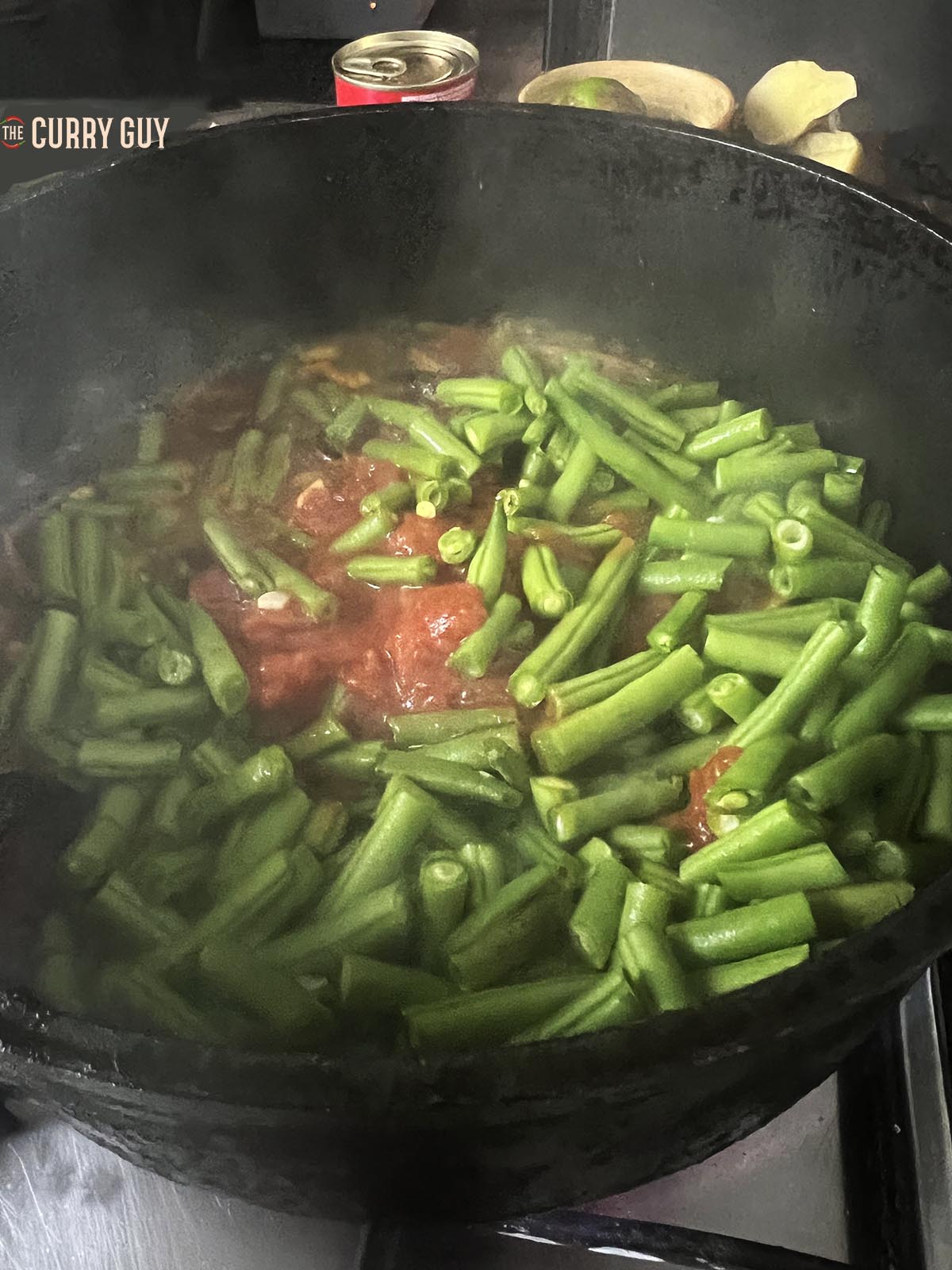 Adding the tomatoes and green beans to the pan.
