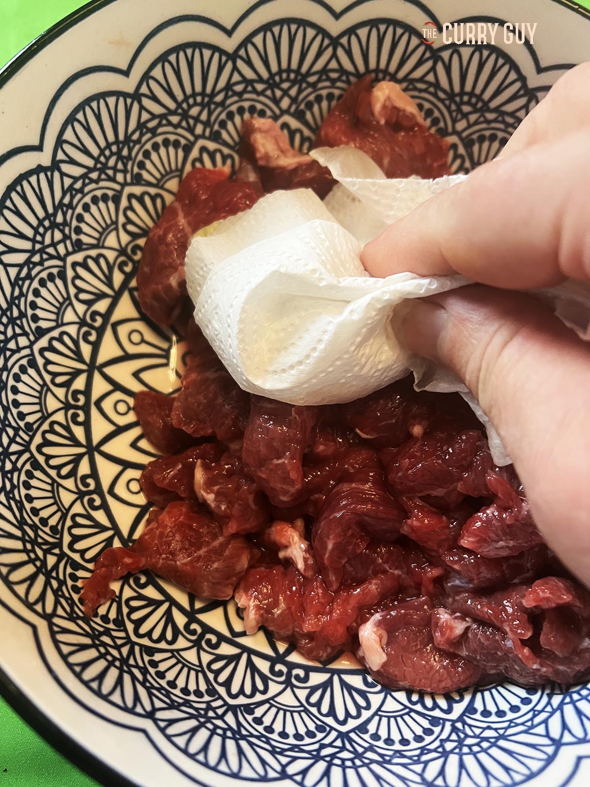 Drying the meat with a paper towel.