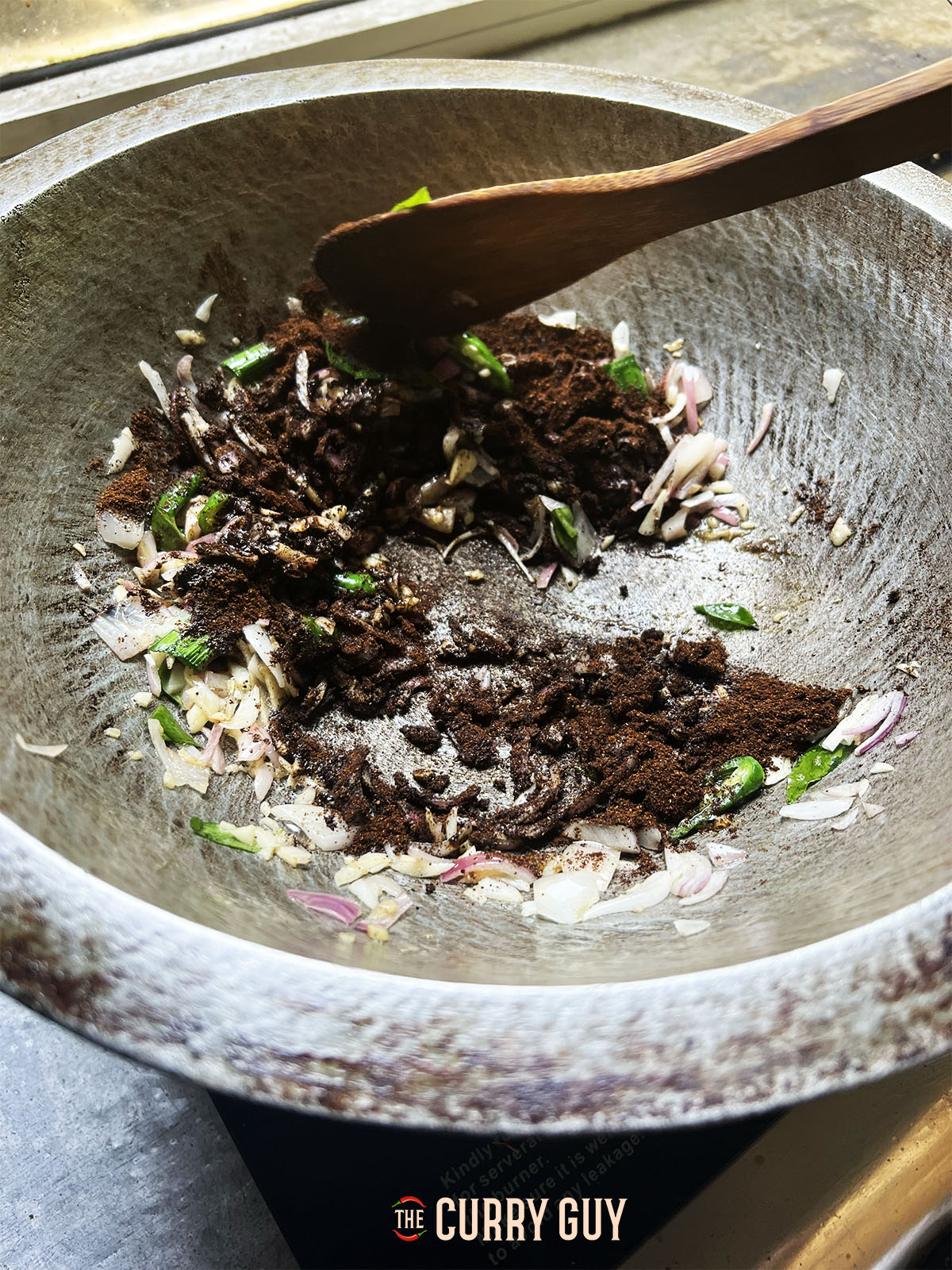 Adding the prepared blackened chilli powder and curry powder to the pan.