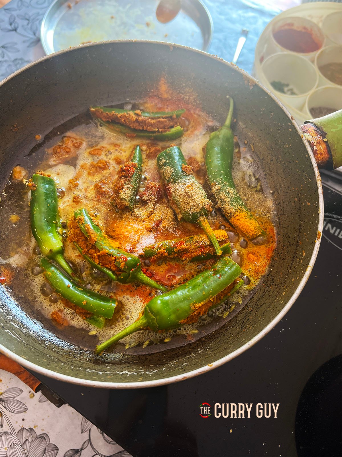 Adding the ground spices to the pan as the chillies are being fried.