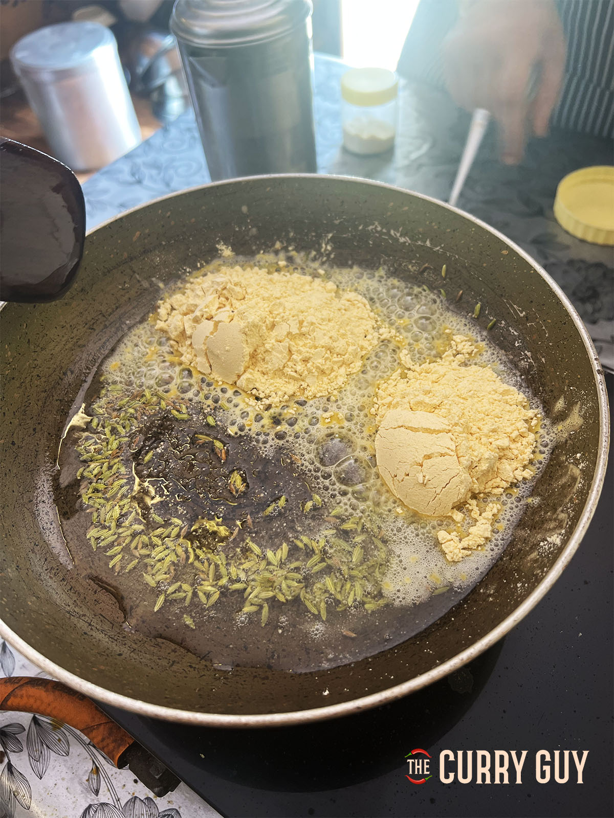 Adding fennel seedsm cumin seeds and asafoetida to the oil and then the gram flour.