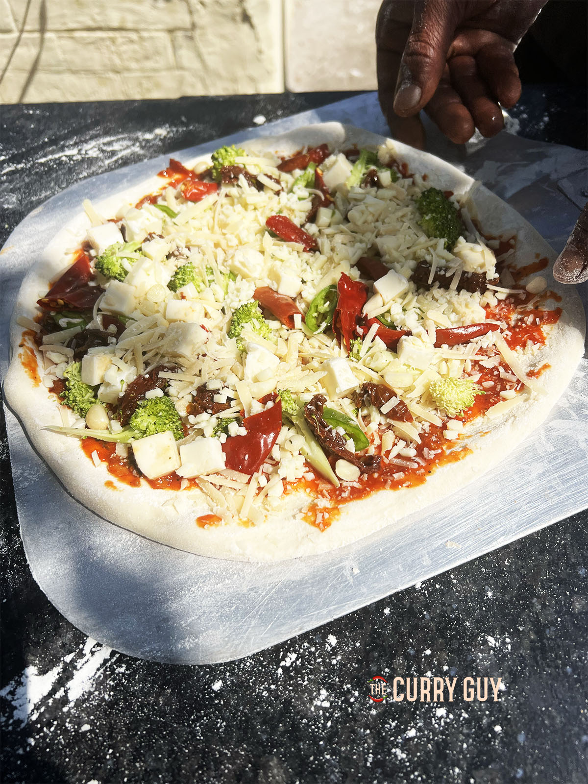 Adding the chillies, cheese and dried chillies to the pizza base.