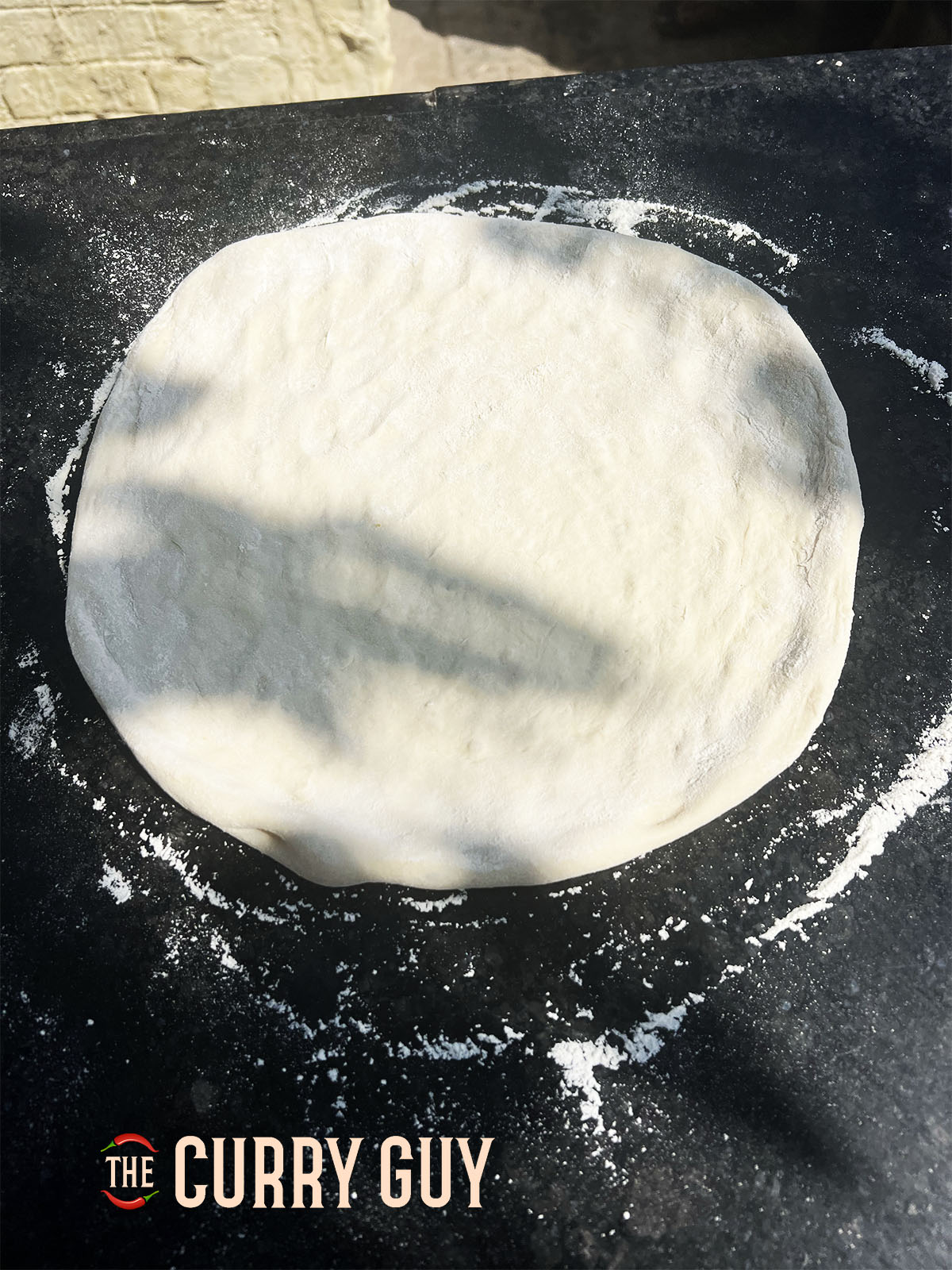 Rolling the dough out into a pizza shape.