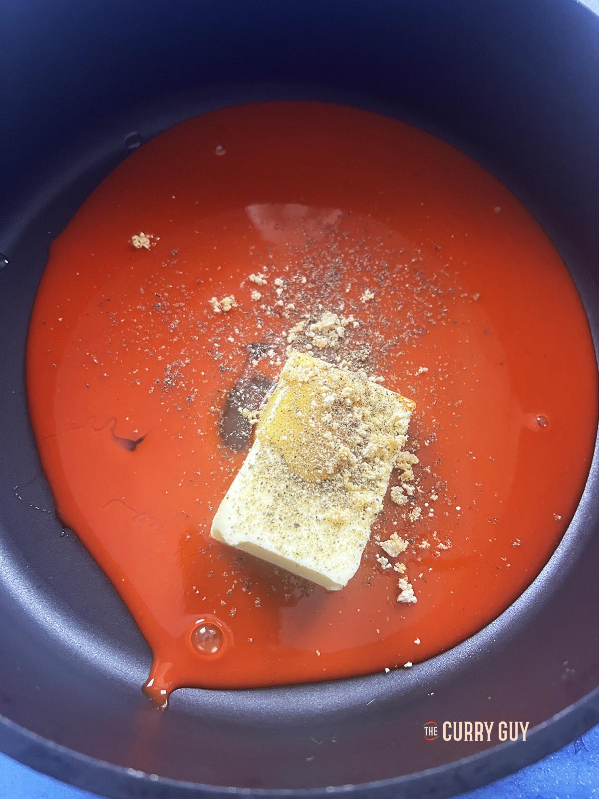 Adding the hot sauce, butter, onion powder and black pepper to a sauce pan.