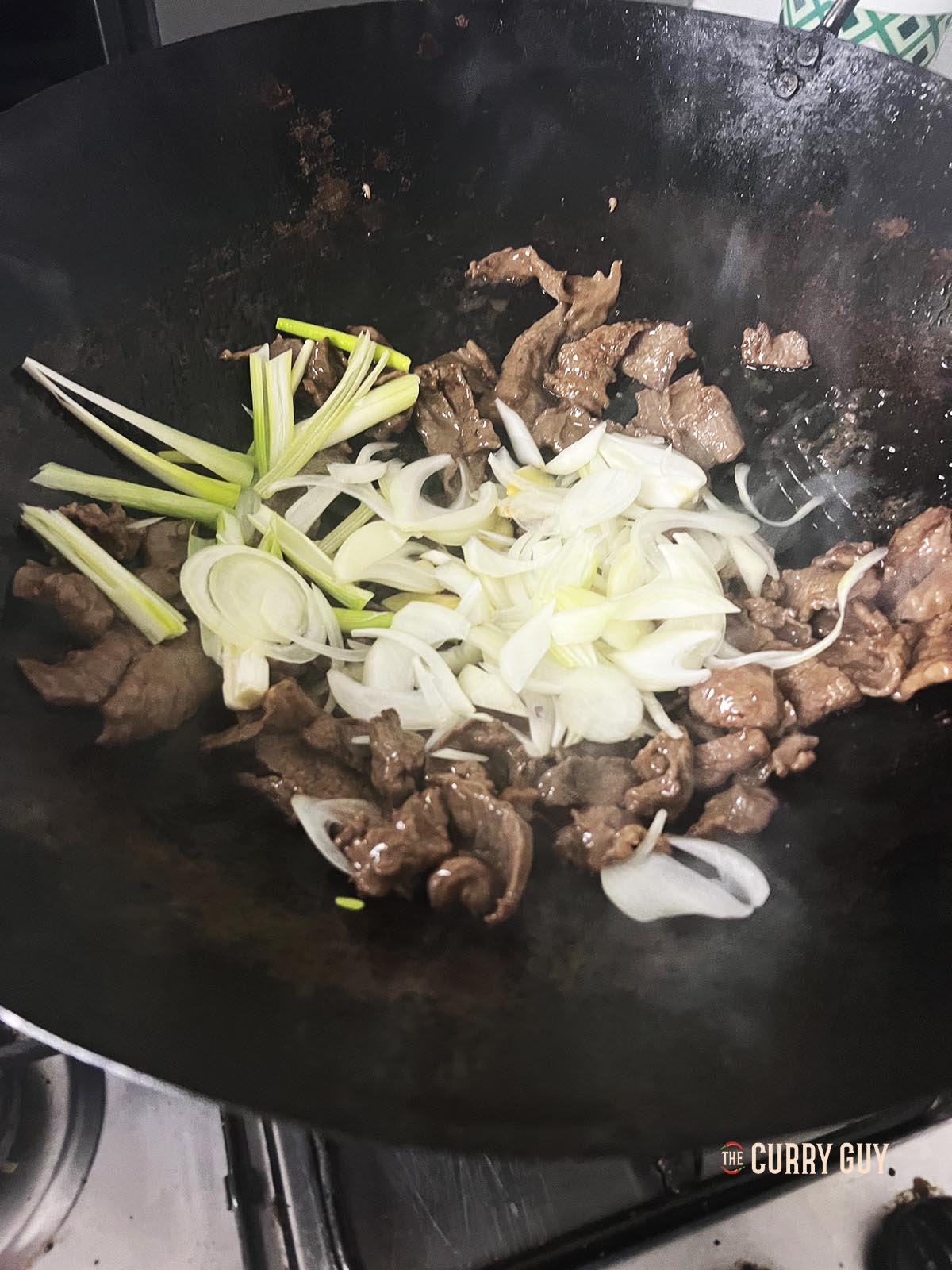 Adding the garlic, ginger and spring onions (scallions) to the wok.