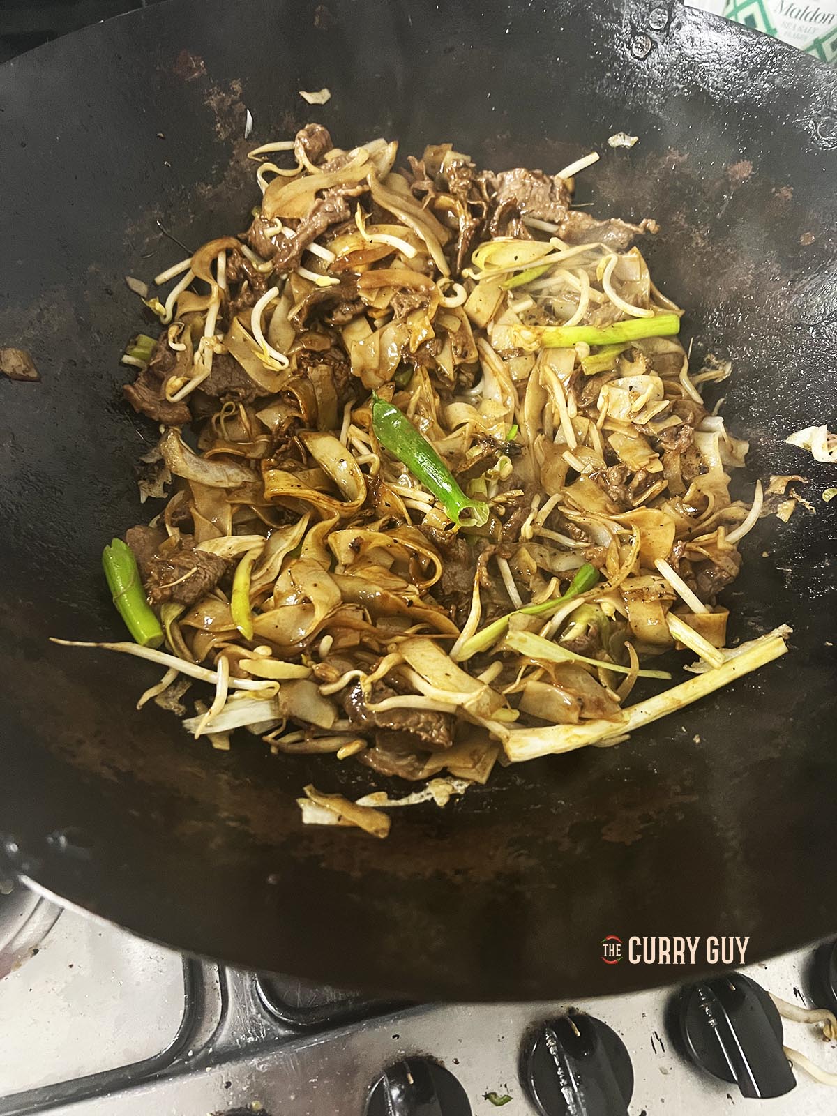 Stirring the contents of the wok to combine.