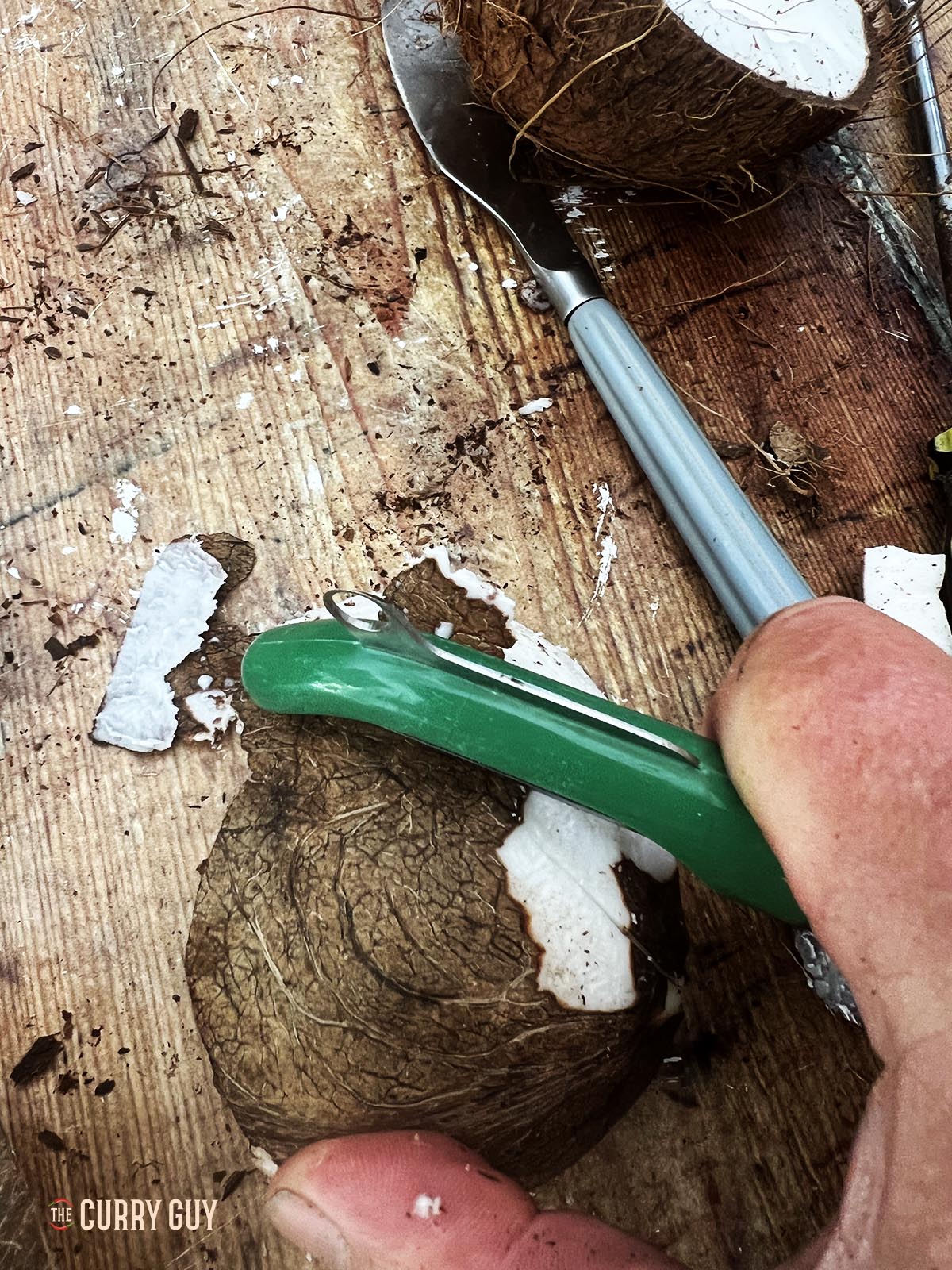 Peeling the skin off the coconut meat with a potato peeler.
