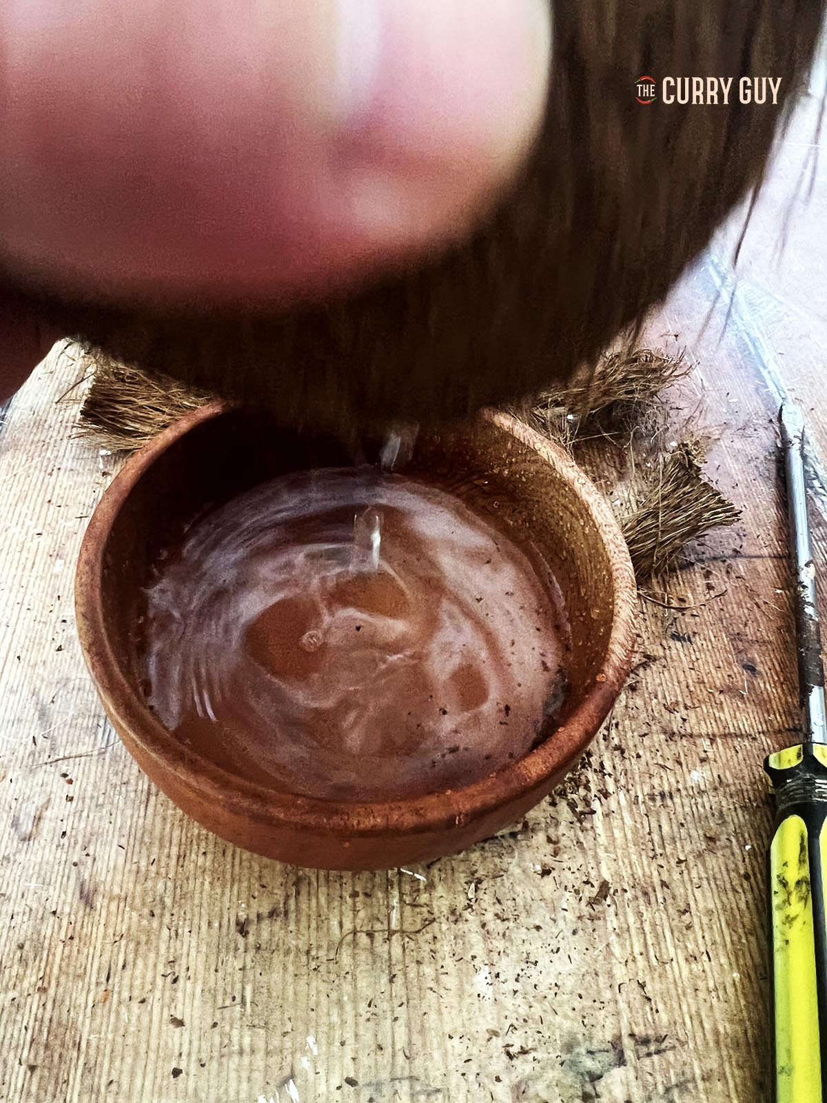 Draining the coconut water out of the coconut.