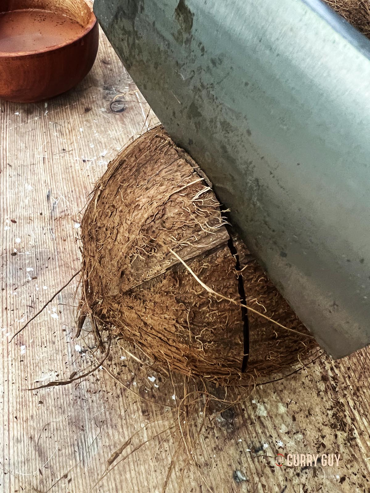Hitting the coconut with a knife to crack it open.