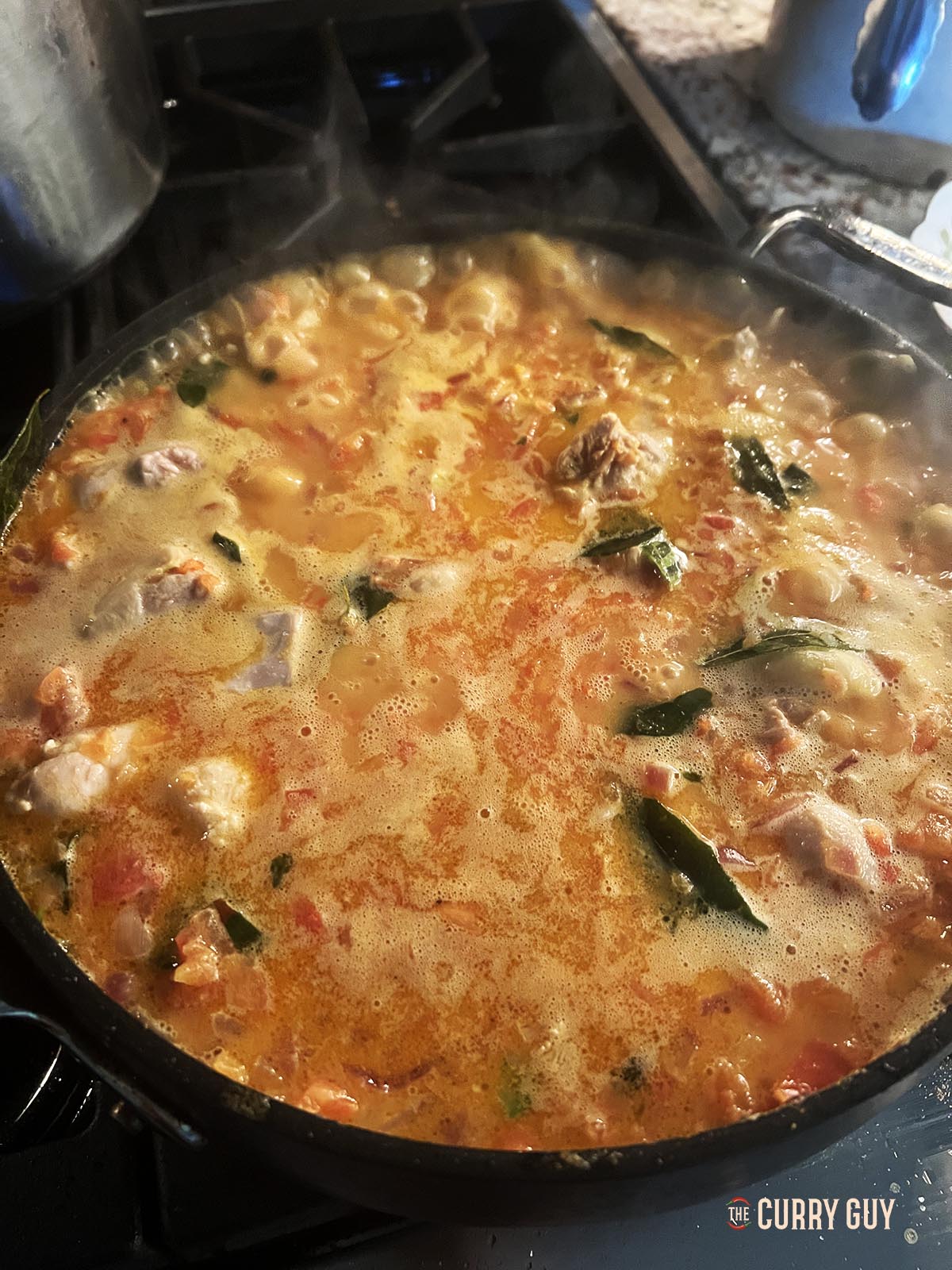 Simmering the chicken in the sauce.