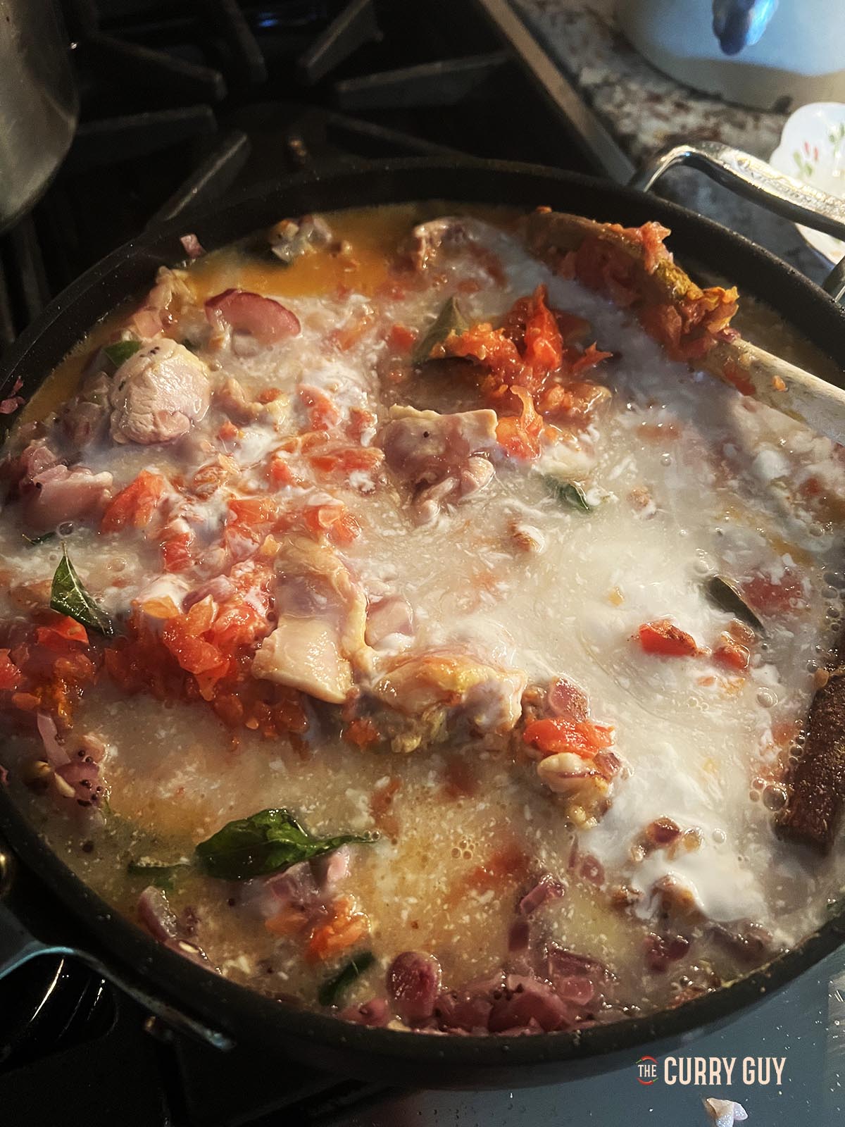 Adding the chopped tomatoes and coconut milk to the pan.