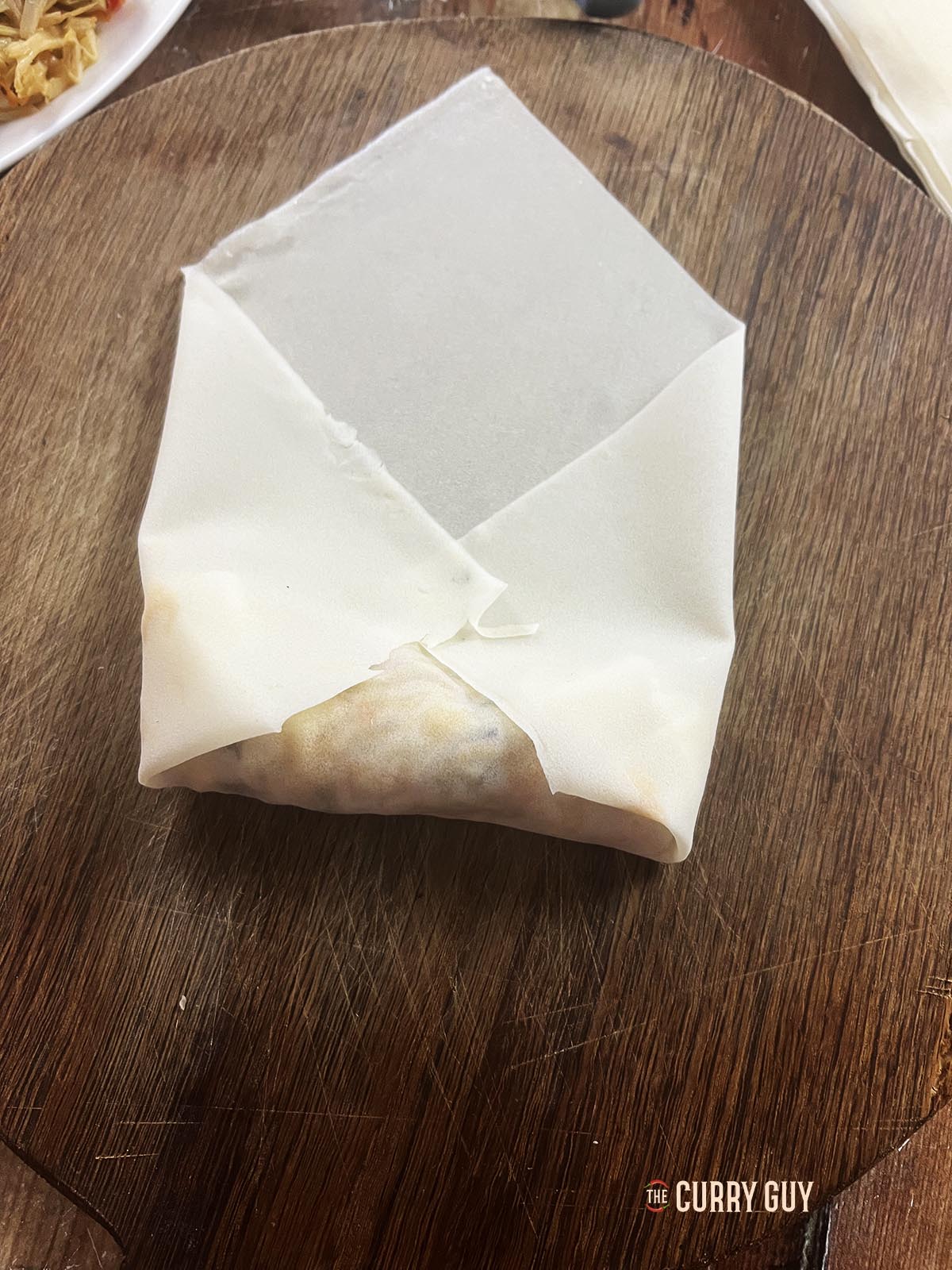 Sealing the filling into the spring roll by folding the right and left corners of the wrapper in.