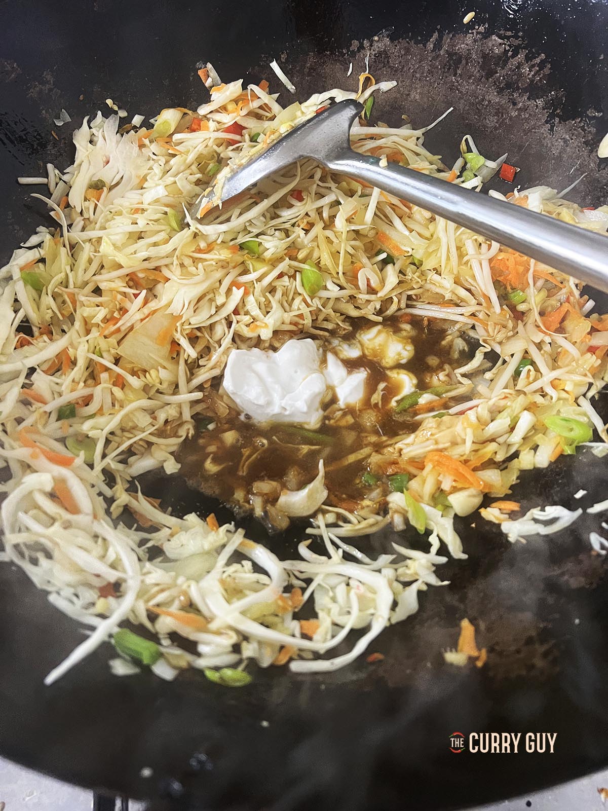 adding the soy sauce, vinegar, coconut milk and sugar to the ingredients in the wok.