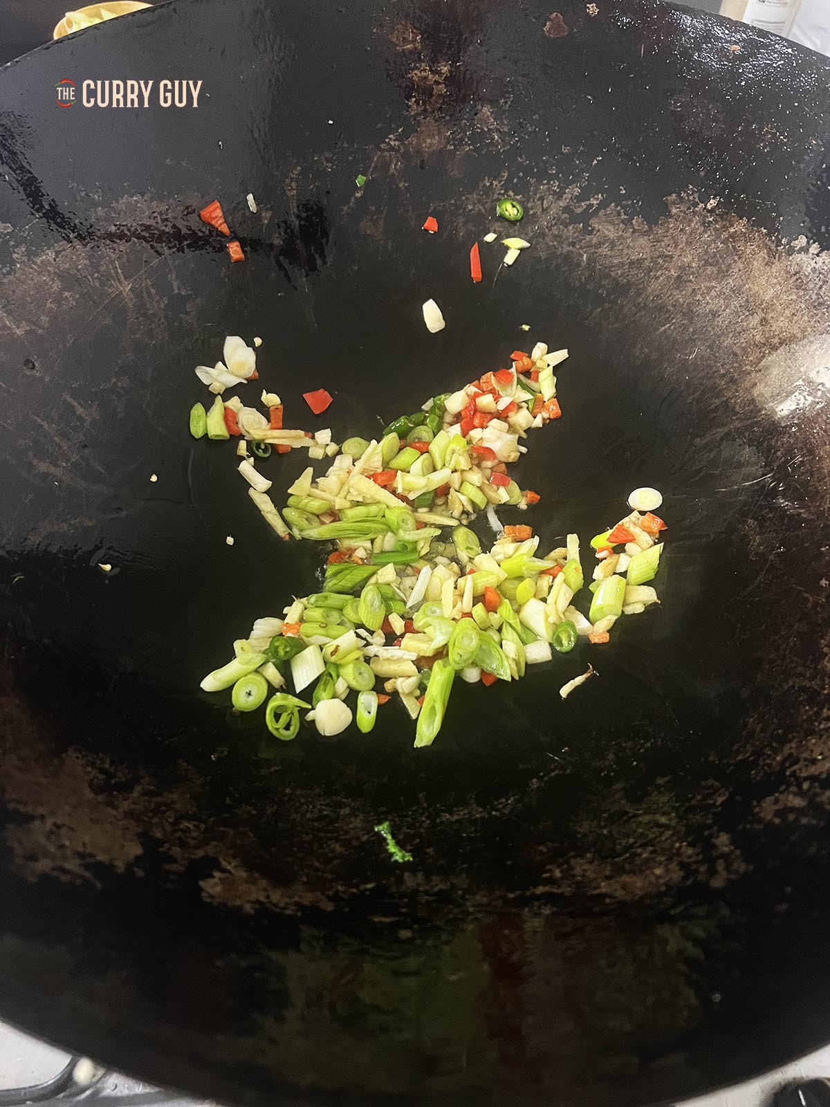 Frying the garlic, ginger, scallions and chillies in a wok.