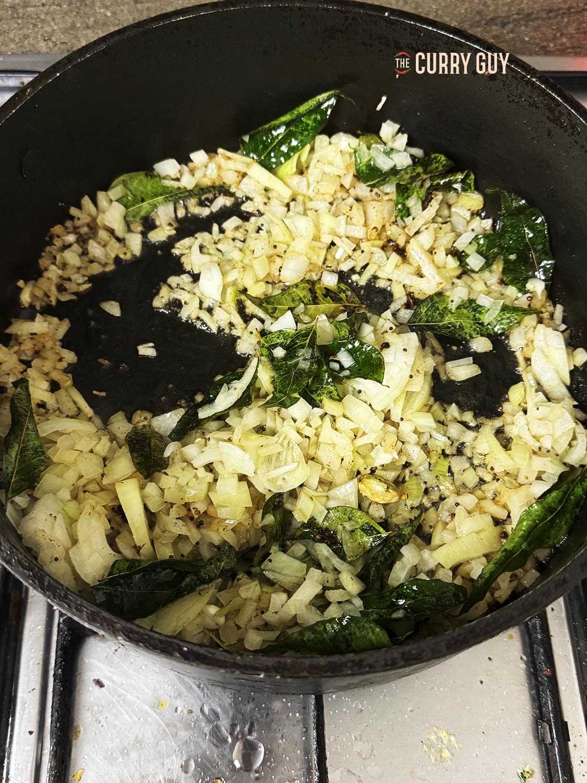 Adding the onions and chillies to the pan to fry until soft and translucent.