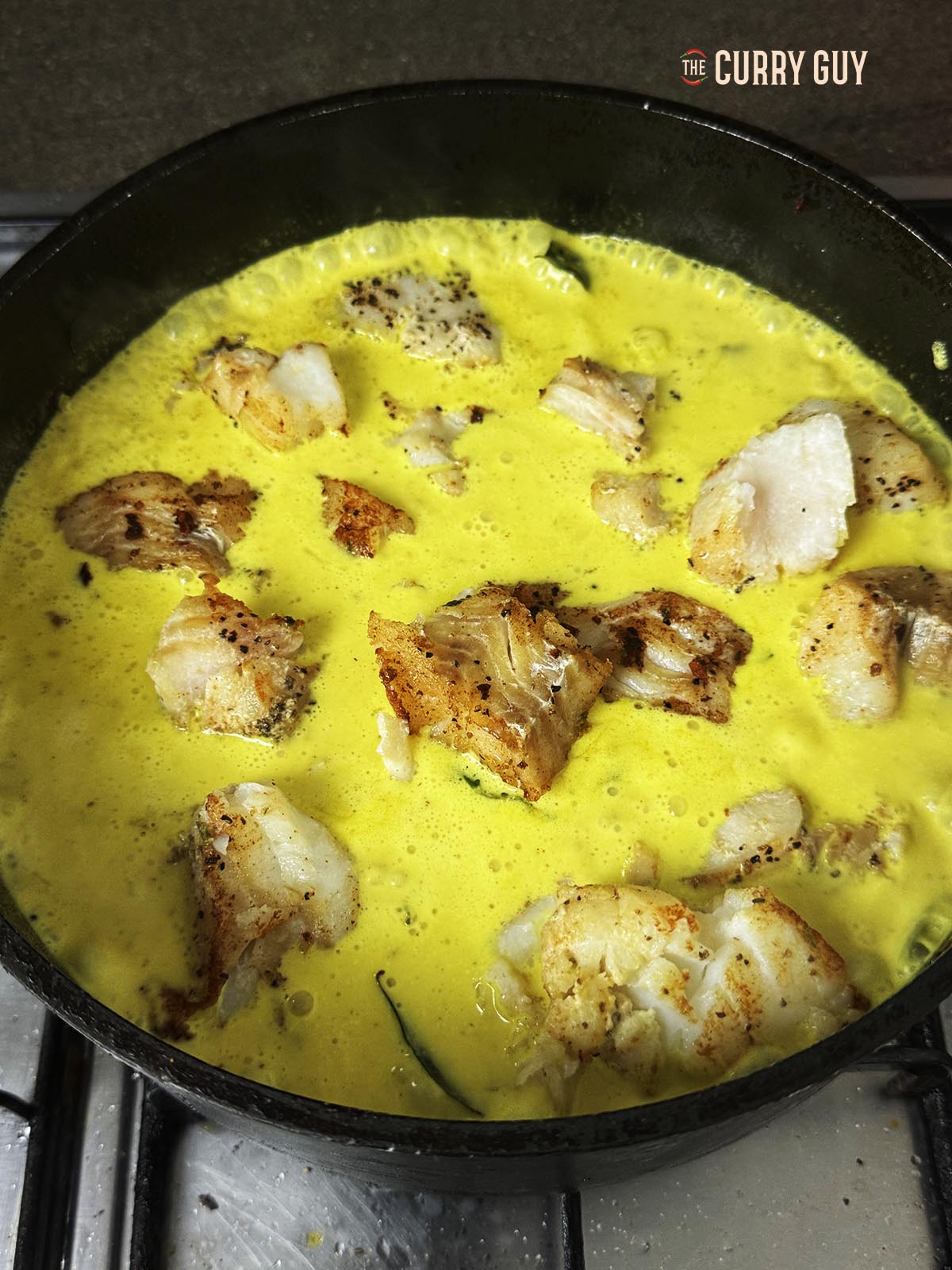 Adding the fish to the pan of simmering sauce.