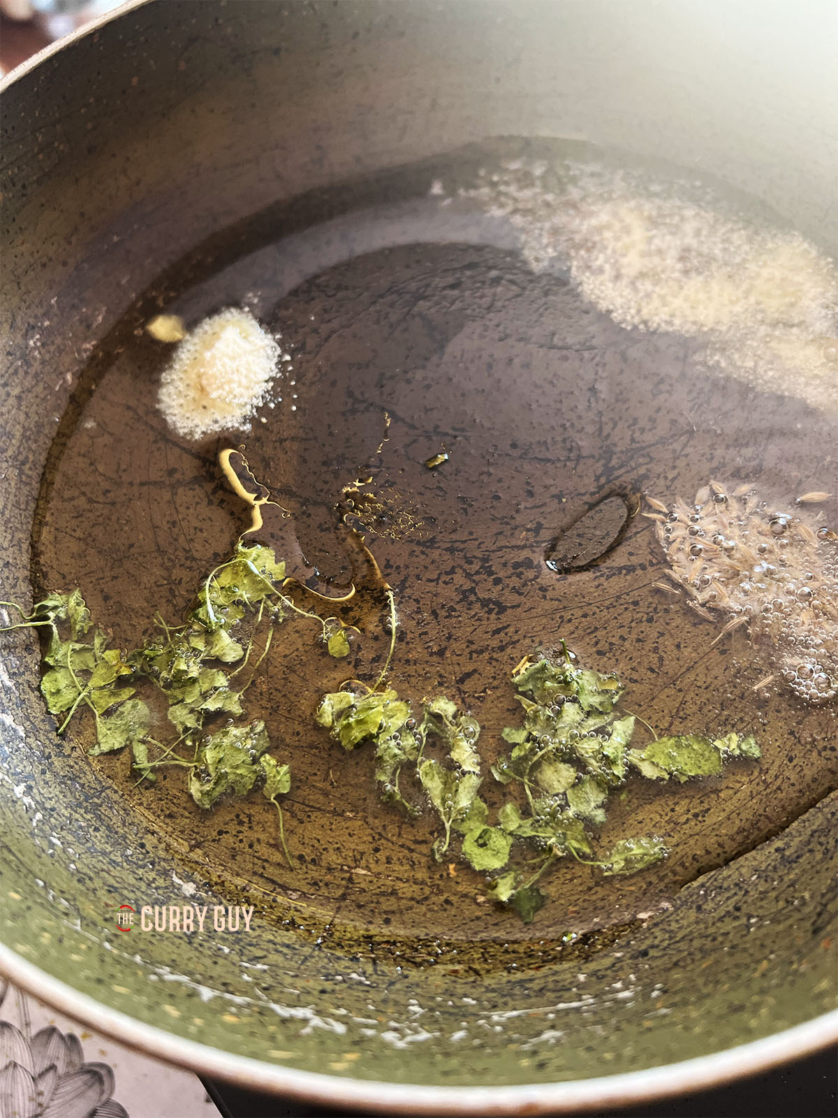 Frying the mustard seeds, cumin powder and fenugreek leaves in oil.