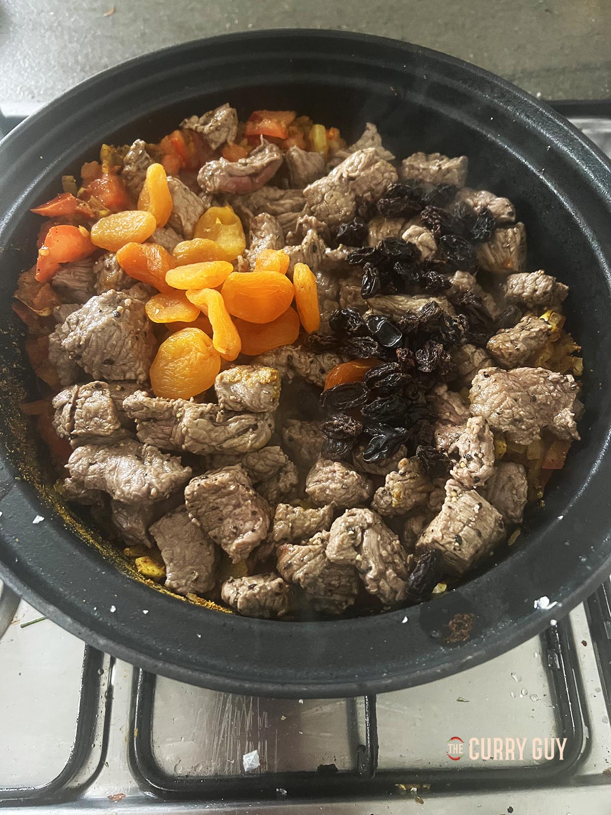 Adding dried apricots and raisins to the pot.