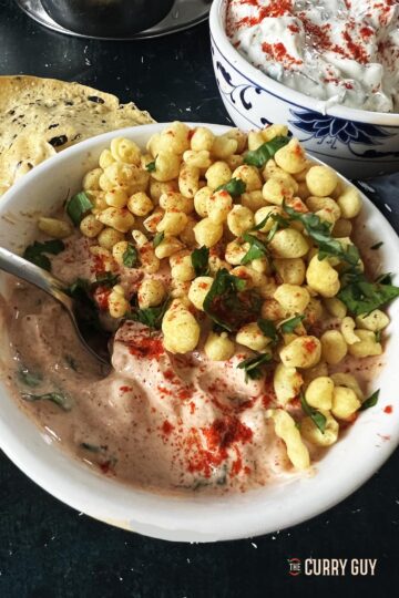 Boondi Raita in a serving bowl garnished with boondi and coriander.
