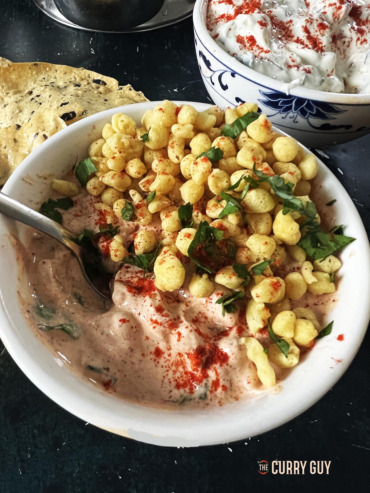 Boondi Raita in a serving bowl garnished with boondi and coriander. 