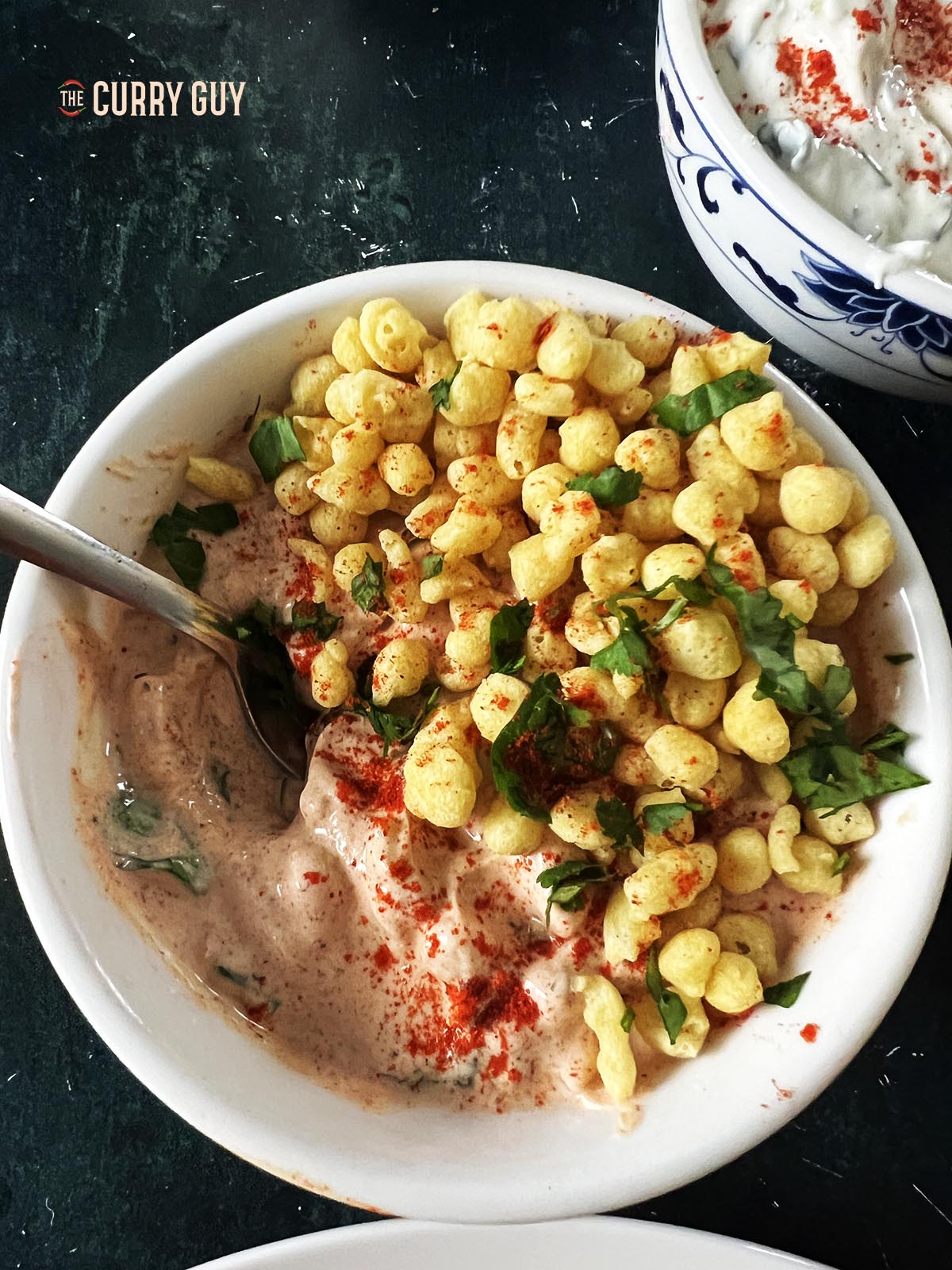 Boondi raita served in a serving bowl and garnished with boondi and coriander. 