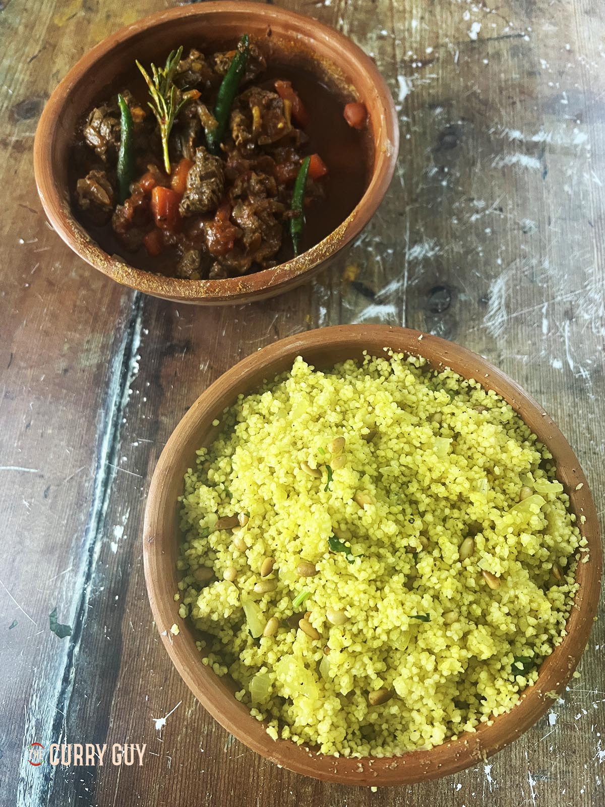 Moroccan couscous in a serving bowl next to a stew. 