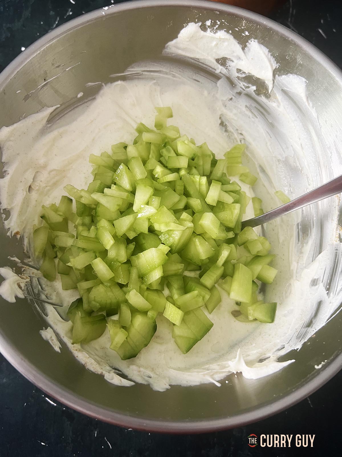 Adding the cucumber to the raita.