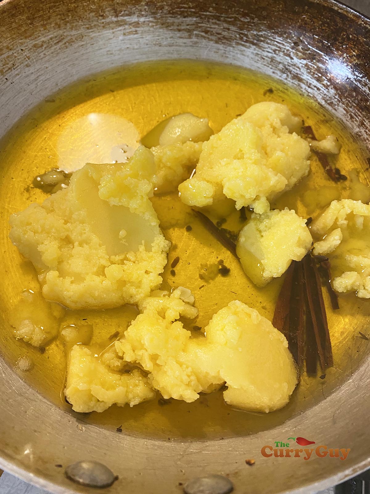 Adding ghee to a pan and bringing to a simmer.