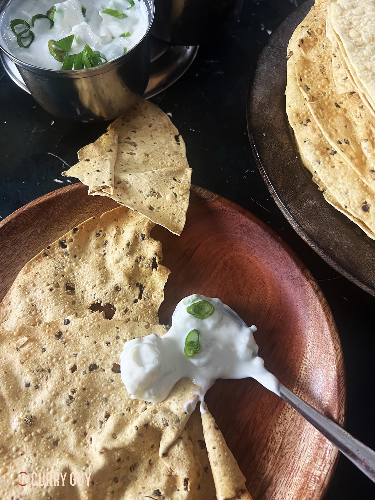 A spoonful of the onion raita by a poppadom.