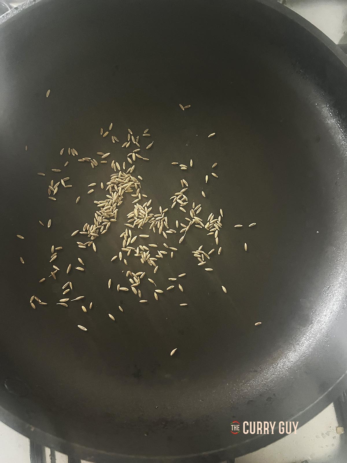 Toasting cumin seeds in a pan.