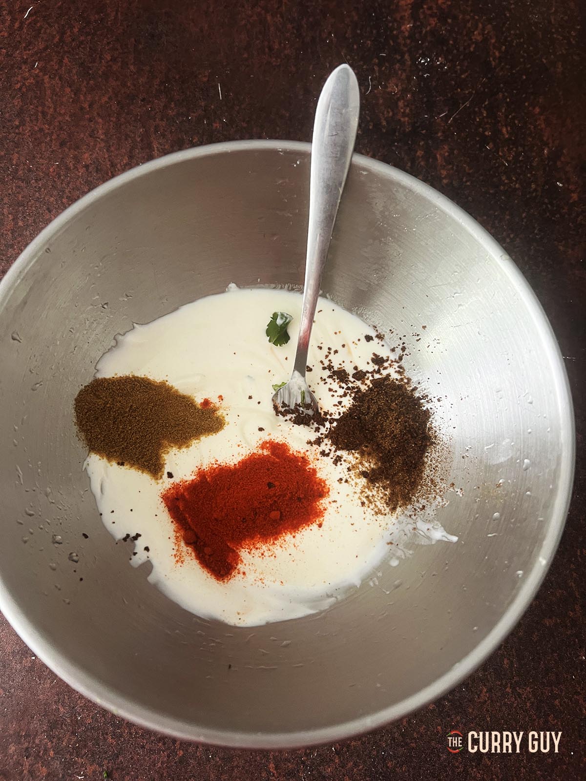 Adding the ground spices to the raita.