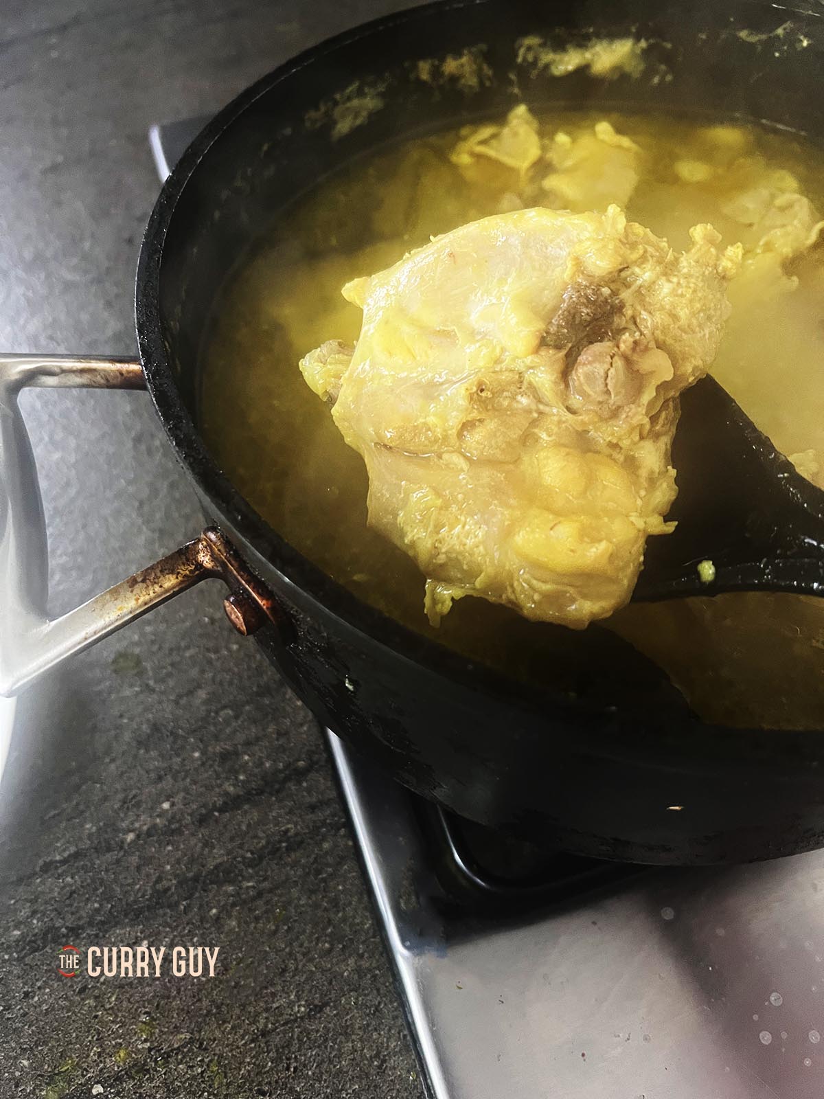 Removing the chicken from the simmering stock.