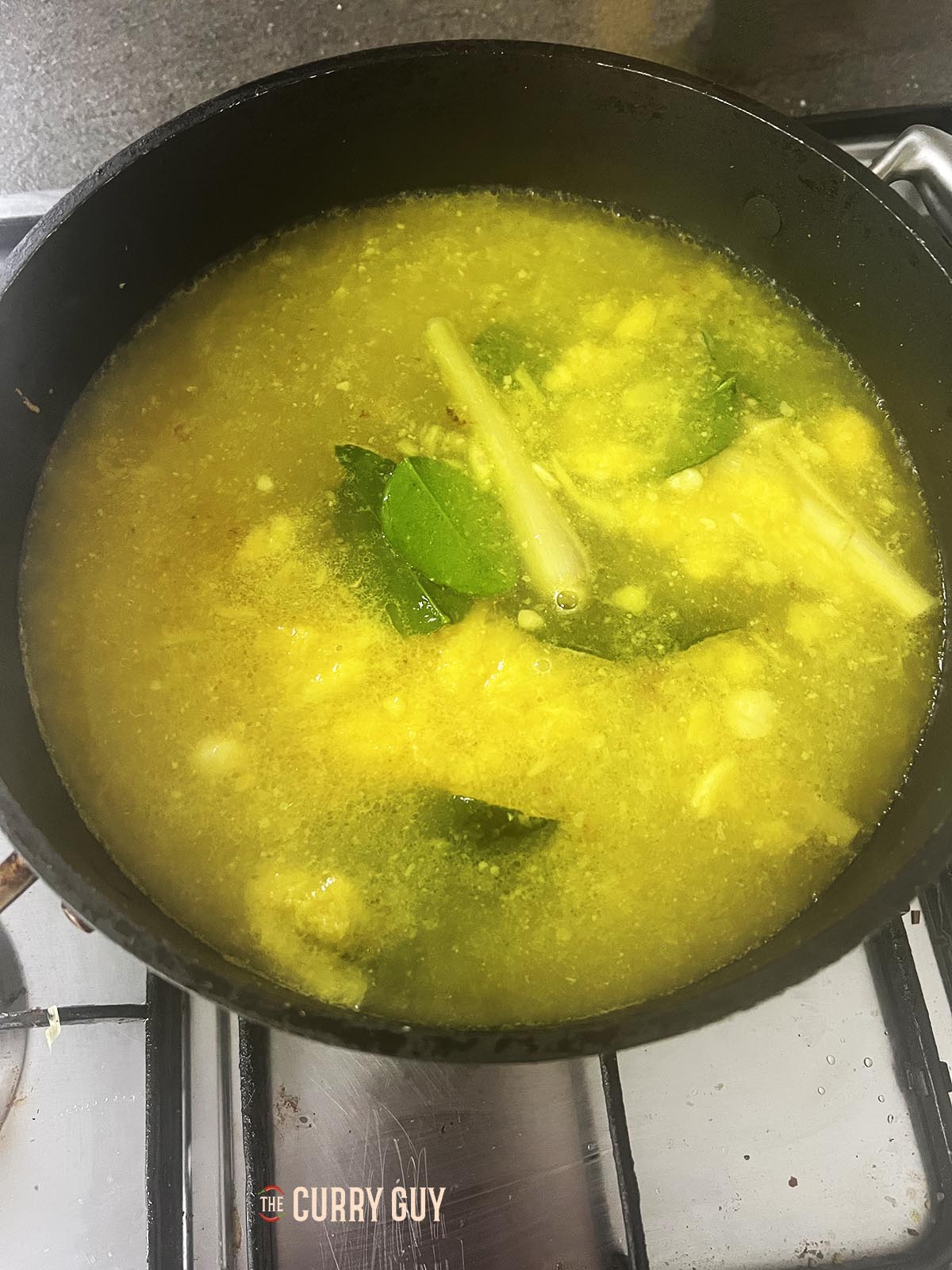 Pouring the stock into the pan and bringing to a simmer.