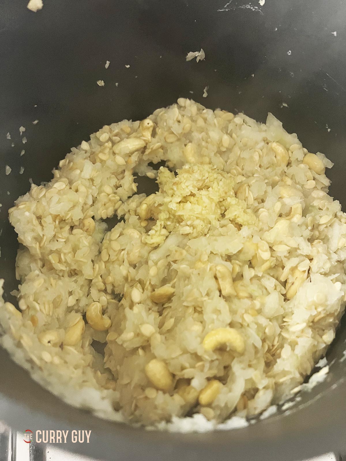 Frying the onion, cashews and melon seeds together in the pan.