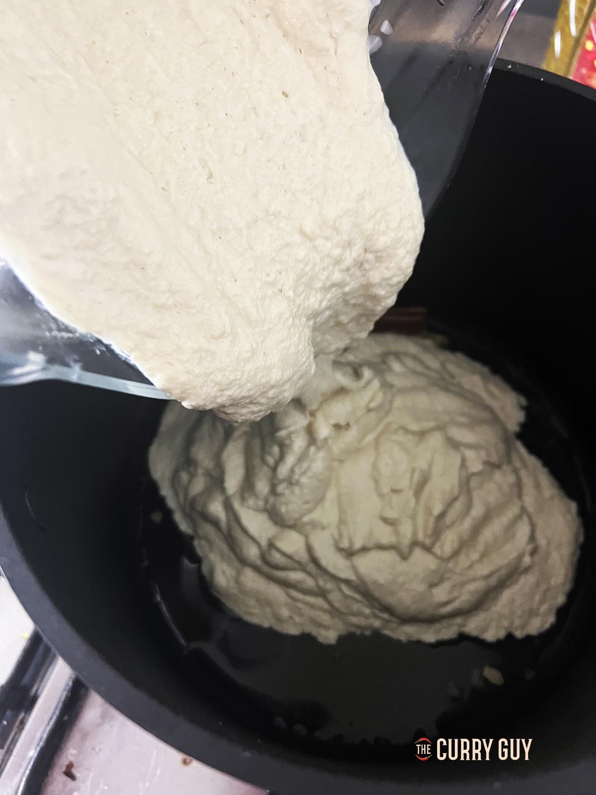 Adding the blended white gravy to the spice infused oil.