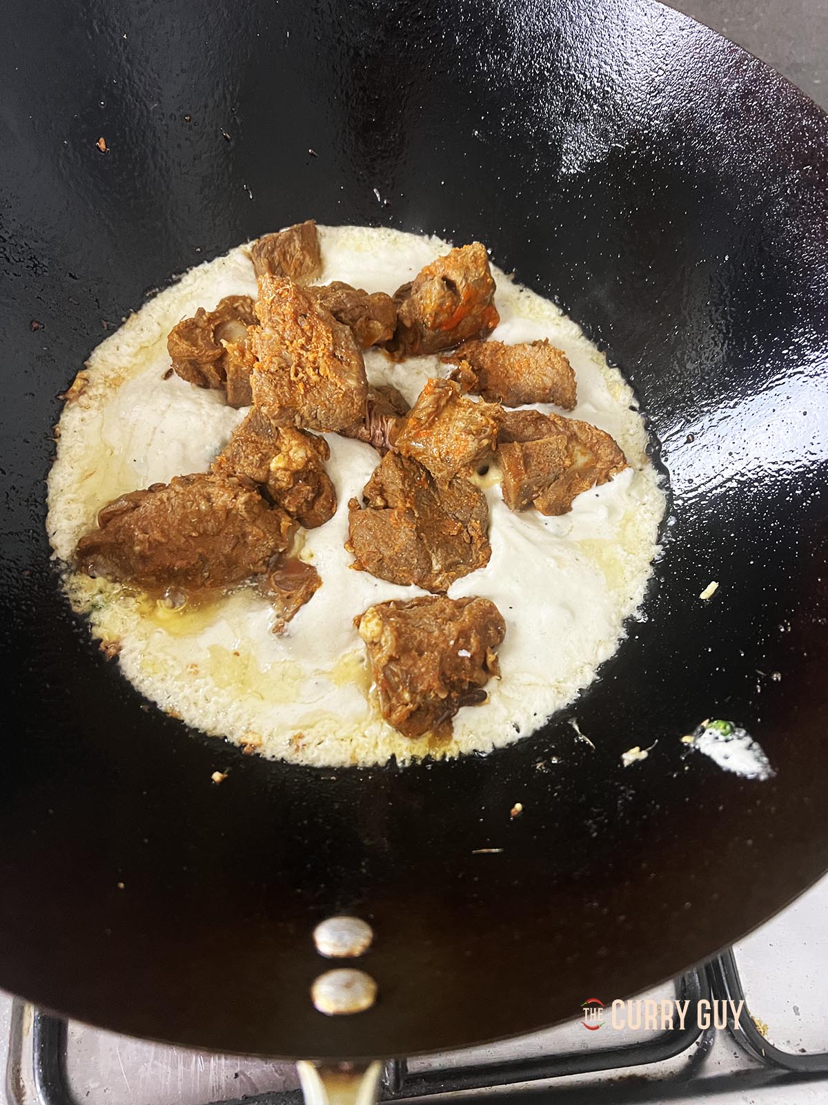 Adding the pre-cooked lamb to the sauce.