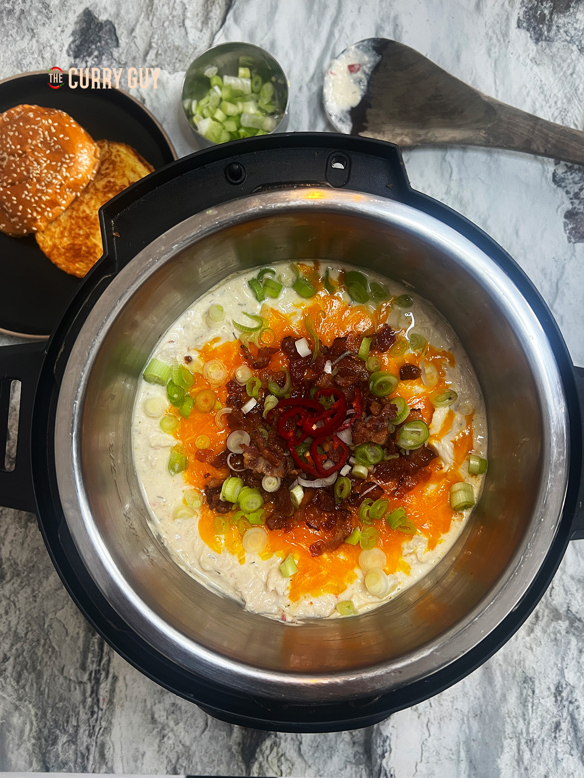 Crack chicken in a crock pot garnished with cheese, bacon and scallions