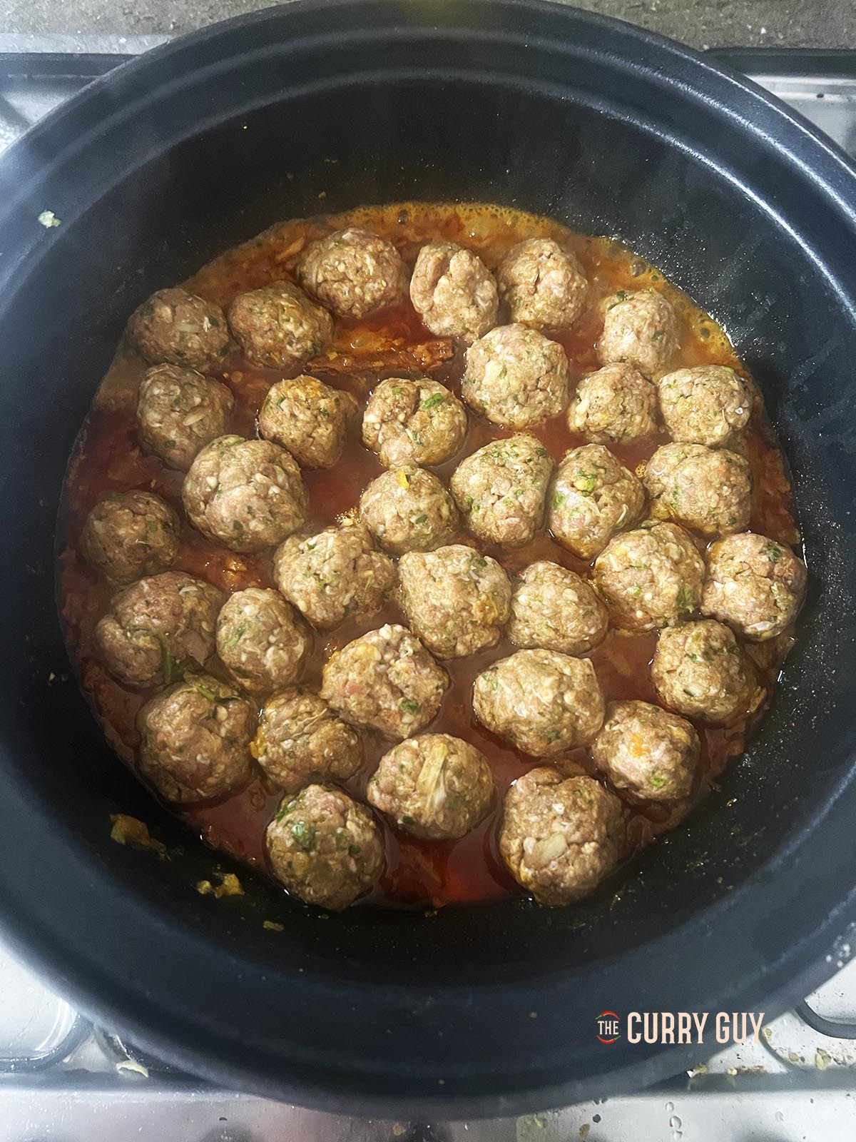 Placing the meatballs in a single later into the sauce.
