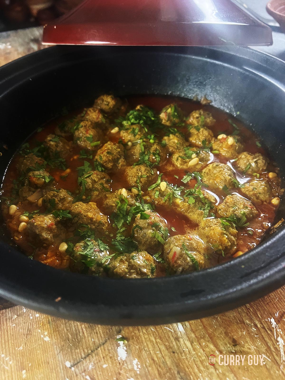 Garnishing the Moroccan meatballs with coriander and toasted pine nuts.