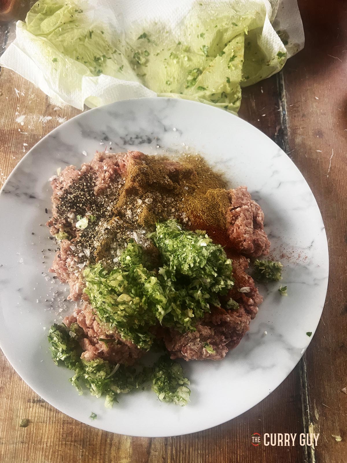 The meat on a plate with all the ingredients to make the meatballs.