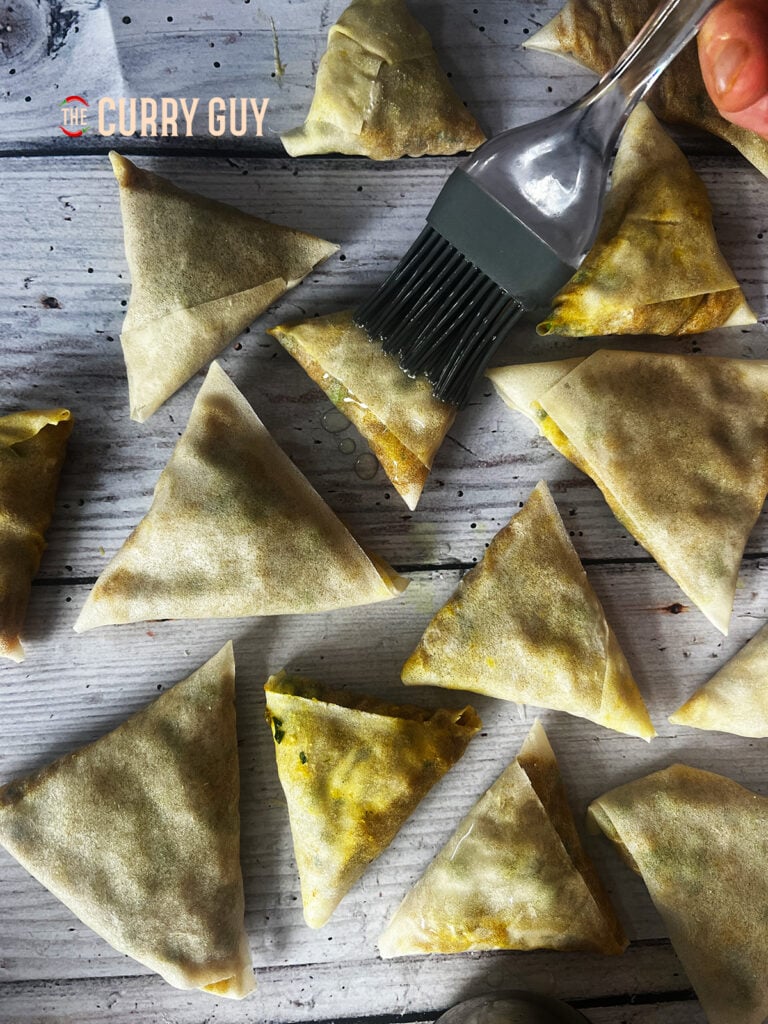 brushing oil on samosas.